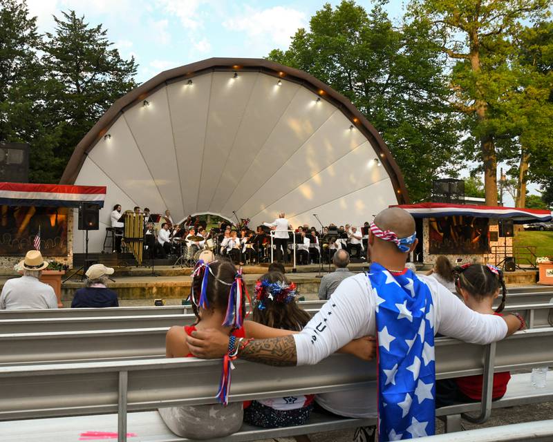 Joseph Clark II of Maple Park sits with his family, (left to right) Scarlet Clark, 7, Lillian Manier, 9, and Joseph Clark III, 5 as the DeKalb Municipal Band performs its annual Independence Day concert at Hopkins Park in DeKalb on Monday July 4, 2022.