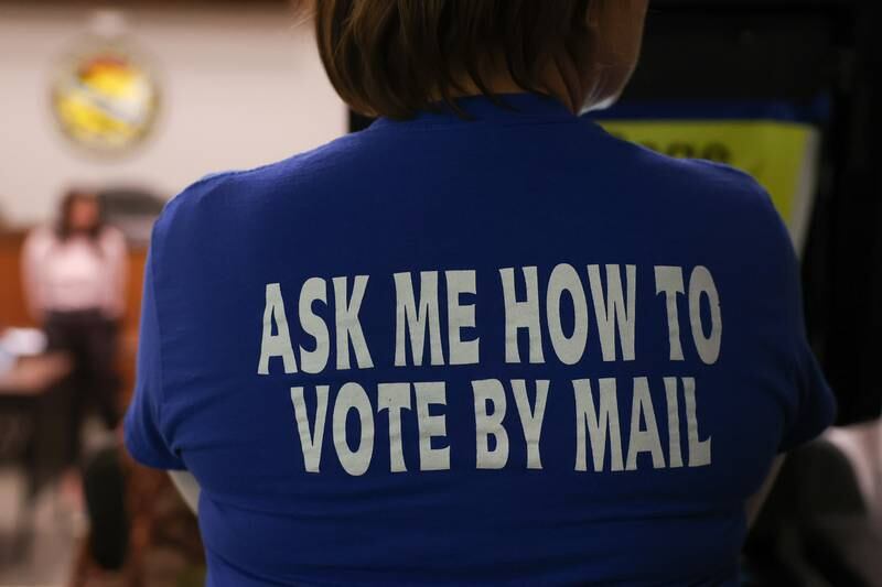 A worker wears a tee shirt about mail in voting as Will County Clerk Lauren Staley Ferry gives instructions before the counting of mail in ballots on Tuesday at the Will County Office Building.