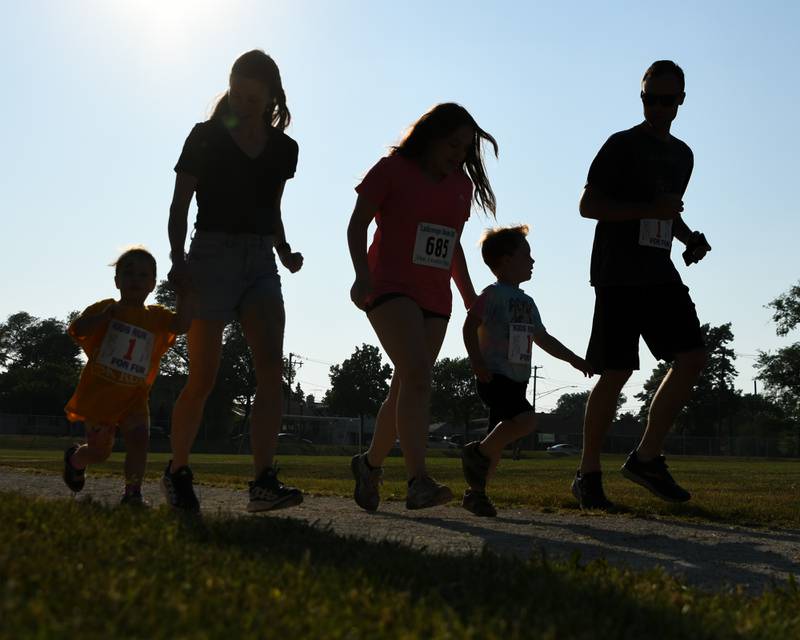 Runners and walkers of all ages take a lap on the track of the Lyons Township practice field during the Leadership event held in La Grange on Friday June 9, 2023.