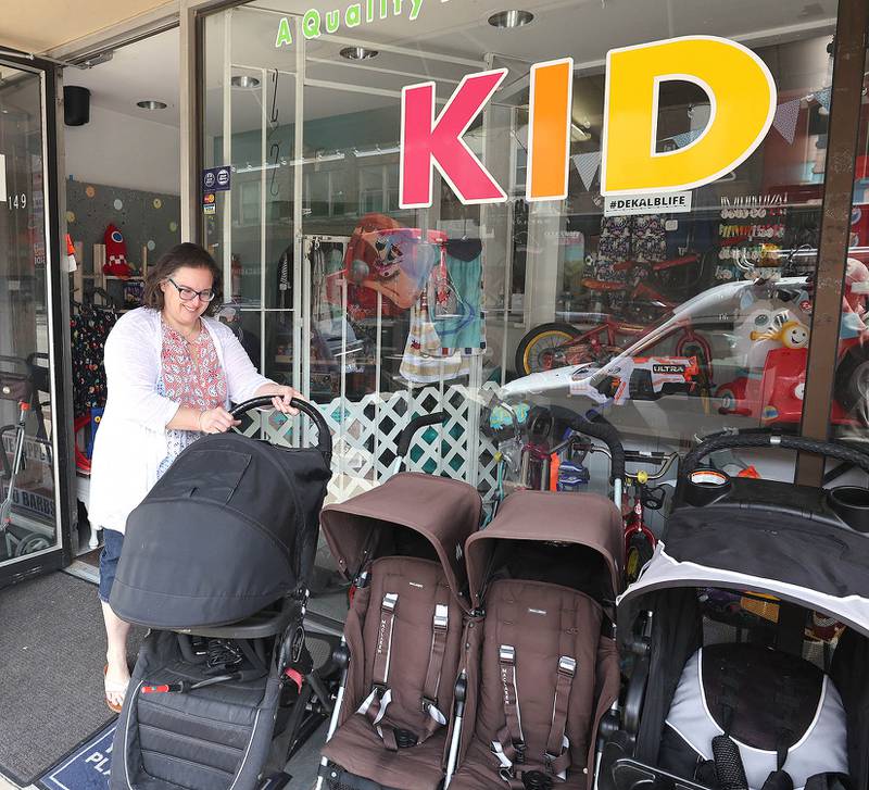 Vickie Obermiller, owner of Kid Stuff at 149 East Lincoln Highway in DeKalb sets some merchandise on the sidewalk Tuesday, May 24, 2022. Road construction will be starting soon on the section of Lincoln Highway between First and Fourth Streets which will afford some businesses more sidewalk space in front of their stores.