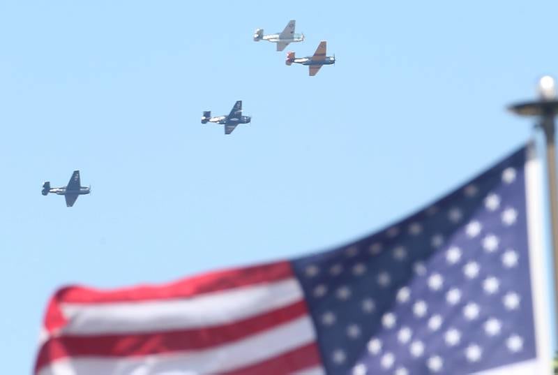 Four TBM aircrafts perform a Missing Man Formation above an American Flag during the 10th annual TBM Avenger Reunion and Airshow on Friday, May 16, 2025 at the Illinois Valley Regional Airport in Peru.