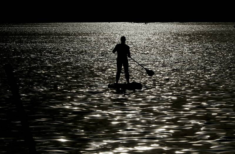 A paddle boarder paddles towards Main Beach for Crystal Lake Park District's Concert in the Park on Tuesday, June 17, 2025, at Main Beach in Crystal Lake. The concert was part of the park district's weekly Tuesday night summer concert series.