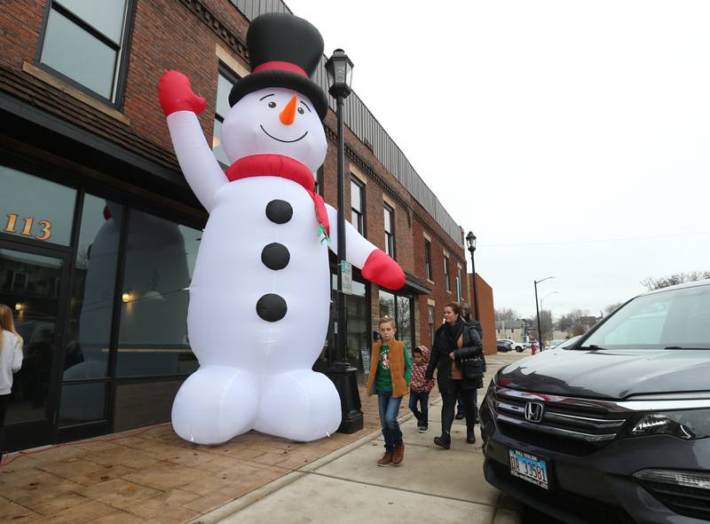 A family walks past a giant inflatable snowman outside the Auditorium Ballroom during the Miracle on First Street event on Saturday, Dec. 2, 2023 in La Salle.