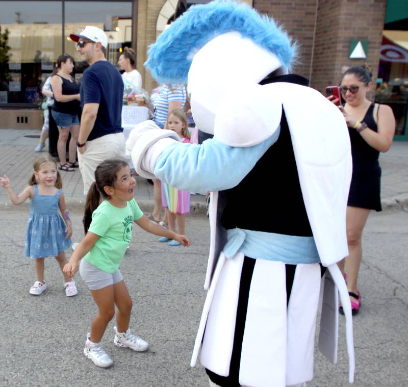 Zoe Arias, 5, of Huntley dances with the Canterbury Elementary School Knight mascot during National Night Out activities in downtown Crystal Lake, Ill. on Thursday, Aug. 7, 2025.
