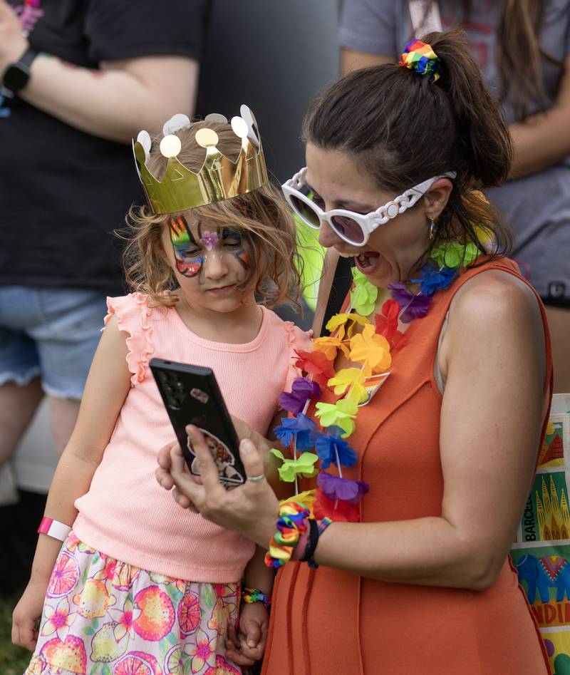 Asa Pakula, 5, looks on as her mom Kegan Pakula of Peru shares photos she had just taken of her daughter and one of the drag performers Saturday during Ottawa Family Pride Festival in Ottawa's Central Park.