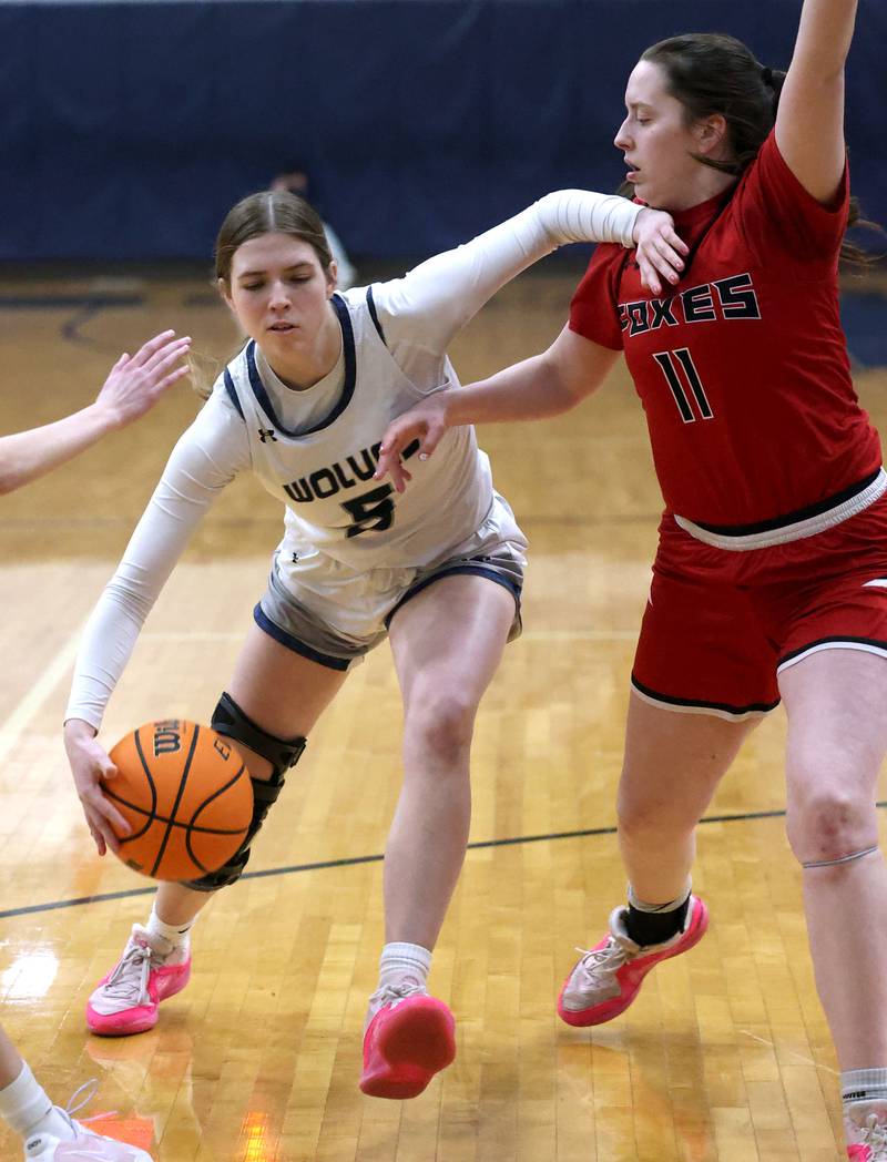Oswego East's Lillie VanDyke drives by Yorkville's Brooke Spychalski during their game Tuesday, Feb. 11, 2025, at Oswego East High School.