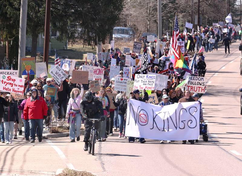 Hundreds of protesters march north Saturday, March 28, 2026, on Sycamore Road in DeKalb during a No Kings march and rally against the federal actions of President Donald Trump and his administration.