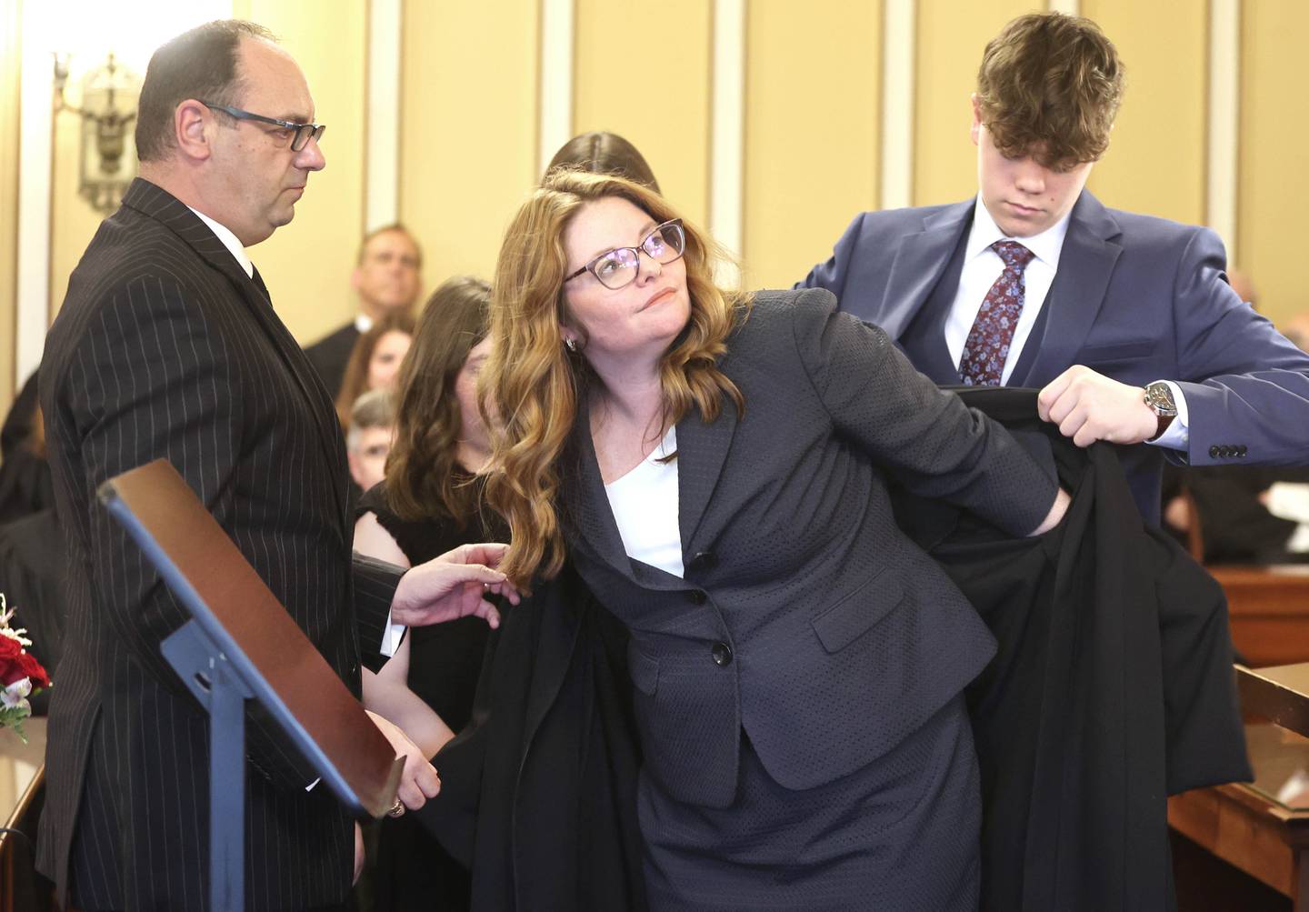 Sarah Gallagher Chami gets a hand from her husband Elie Chami (left) and her son Michael during the presentation of the robe after she was sworn in as an associate judge of the 23rd Judicial Circuit Friday May 6, 2022, at the DeKalb County Courthouse in Sycamore.