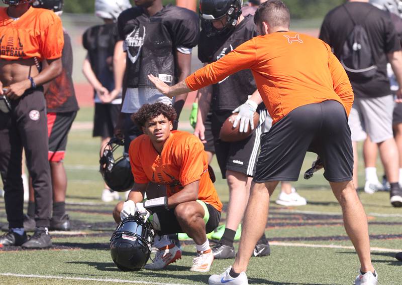 DeKalb's Xavier Dandridge gets some instruction from head coach Derek Schneeman during a joint football practice with Kaneland Thursday, July 14, 2022, at DeKalb High School.