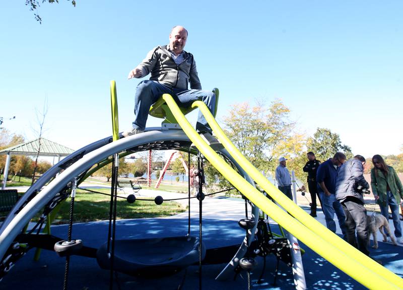 Ottawa commissioner Tom Ganiere slides down new playground equipment during The City of Ottawa ribbon-cutting ceremony on Thursday, Oct. 17, 2024 at Allen Park in Ottawa. Commissioner Marla Pearson (center) cuts the ribbon on a 1.5 million dollar completion of a playground and other improvements to the park. The project was partially funded by a $506,000 IDNR Open Space Land Acquisition and Development grant. The new enhancements to Allen Park include accessible sidewalks leading to the upper plateau, featuring a modern playground and hillside play area with safe, poured-in-place surface for children of all abilities. The area also includes a shelter, bench swing with views of the Illinois River and a stone council ring for relaxation and community gatherings. 
A paved quarter-mile looped walking trail along the scenic banks of the Illinois River, two designated gaming areas, one with four bag toss stations and another with two chess-checkers tables and two ping-pong tables, all designed to promote social interaction and recreation. The sculptures will be repainted in the spring of 2025.