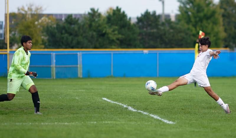 Oswego’s David Castro (14) shoots the ball against Oswego East's Javier Ruiz (1) during a soccer match at Oswego East High School on Tuesday, Sept. 26, 2023.