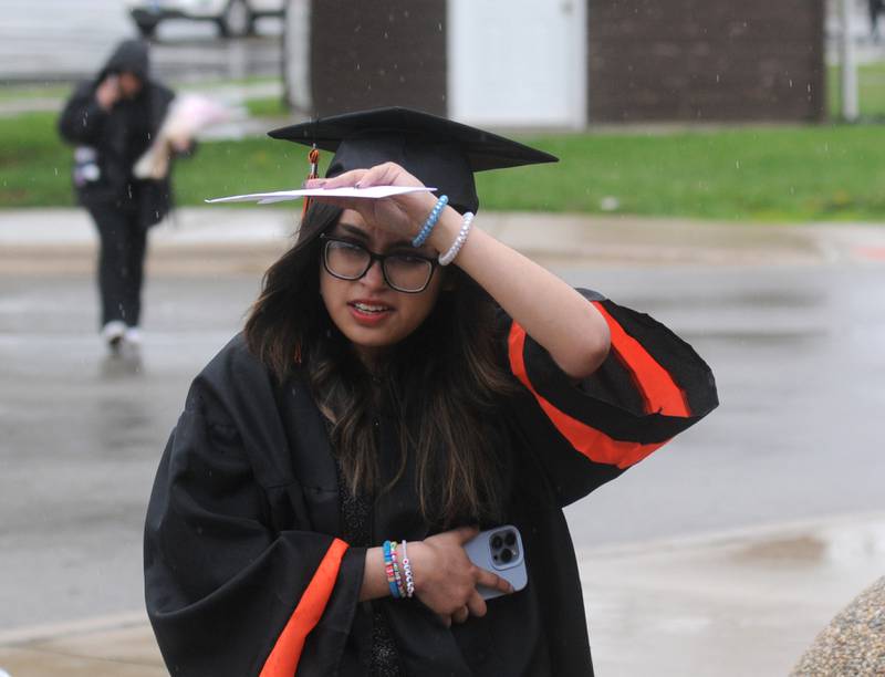 Alondra Hernandez tries to keep dry as she walks into the school Saturday, May 21, 2022, for McHenry High School’s 102nd Commencement Ceremony in the gym of the Upper Campus. The ceremony was moved inside and split into two ceremonies because of the rainy weather.