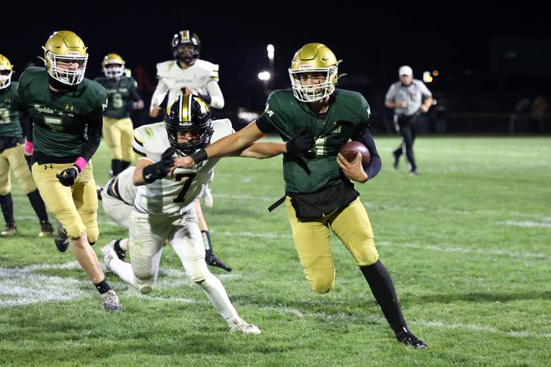 Bishop McNamara quarterback Karter Krutsinger evades a tackle by Herscher's Gaige Brown during Bishop McNamara's 38-14 victory in the IHSA Class 3A first round playoff game on Friday, Oct. 31, 2025.