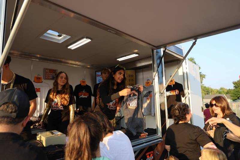 McHenry High School students work the Warrior Shack during the homecoming game on Friday, Sept. 29, 2023. Much of the spirit wear sold at the Warrior Shack is designed by students and made by its production class.