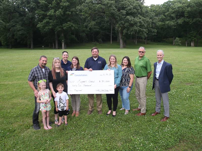 (From left) Bucky Crank, Melissa Crank, Kaibrey Crank, Kaison Crank, Constellation Energy employees Val Runner, Amanda Grabowski, John Van Fleet, and Abby Huff, Streator mayor Tara Bedei and Edward Jones financial advisor Gary Wheeler pose for a photo at the site of a future playground of Logan's Oasis on Monday, June 16, 2025 at Marilla Park in Streator.