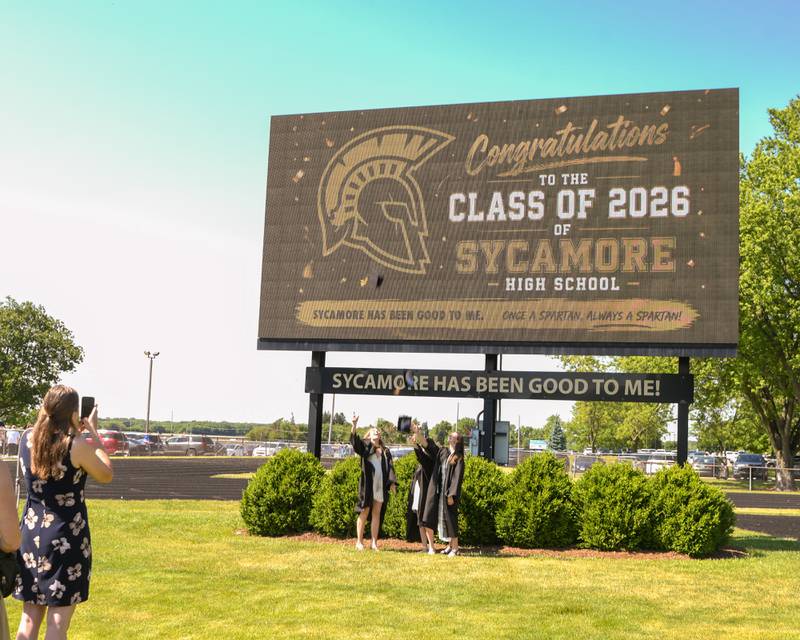 Sycamore High School graduates Ashley Tucker, left, Natalee Hernandez, center and Julia Peska pose for a photo in front of the football field scoreboard after the completion of the graduation ceremony on Sunday May 24, 2026, held at Sycamore High School.