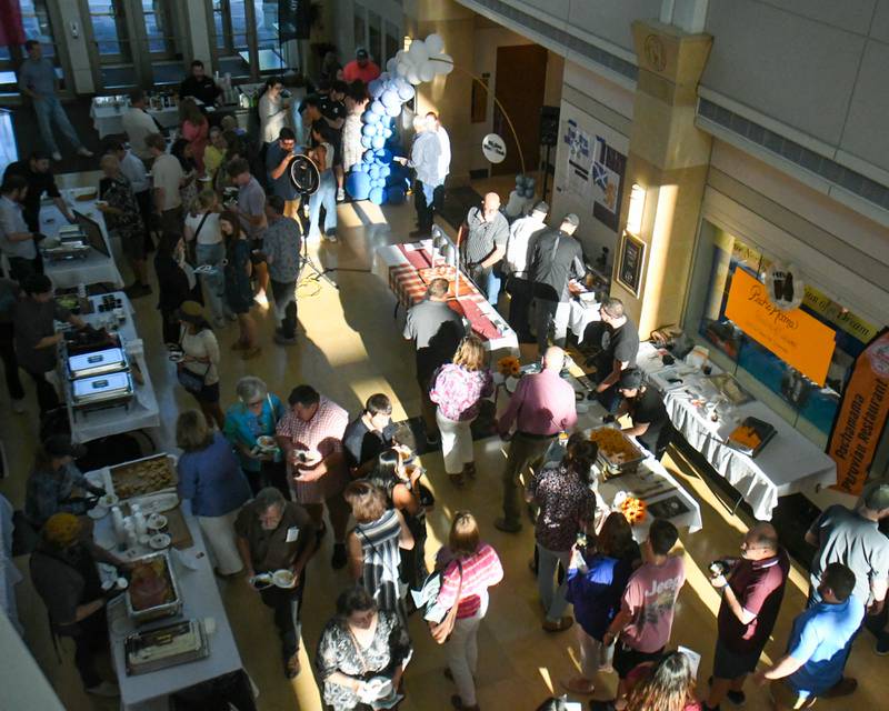Community members stand at tables and go through a line of dishes made by professional chefs  during the 20th anniversary of 50 Men Who Cook, an annual fundraiser hosted by CASA DeKalb County at the Barsema Alumni and Visitors Center at Northern Illinois University in DeKalb on Saturday, Aug. 10, 2024.