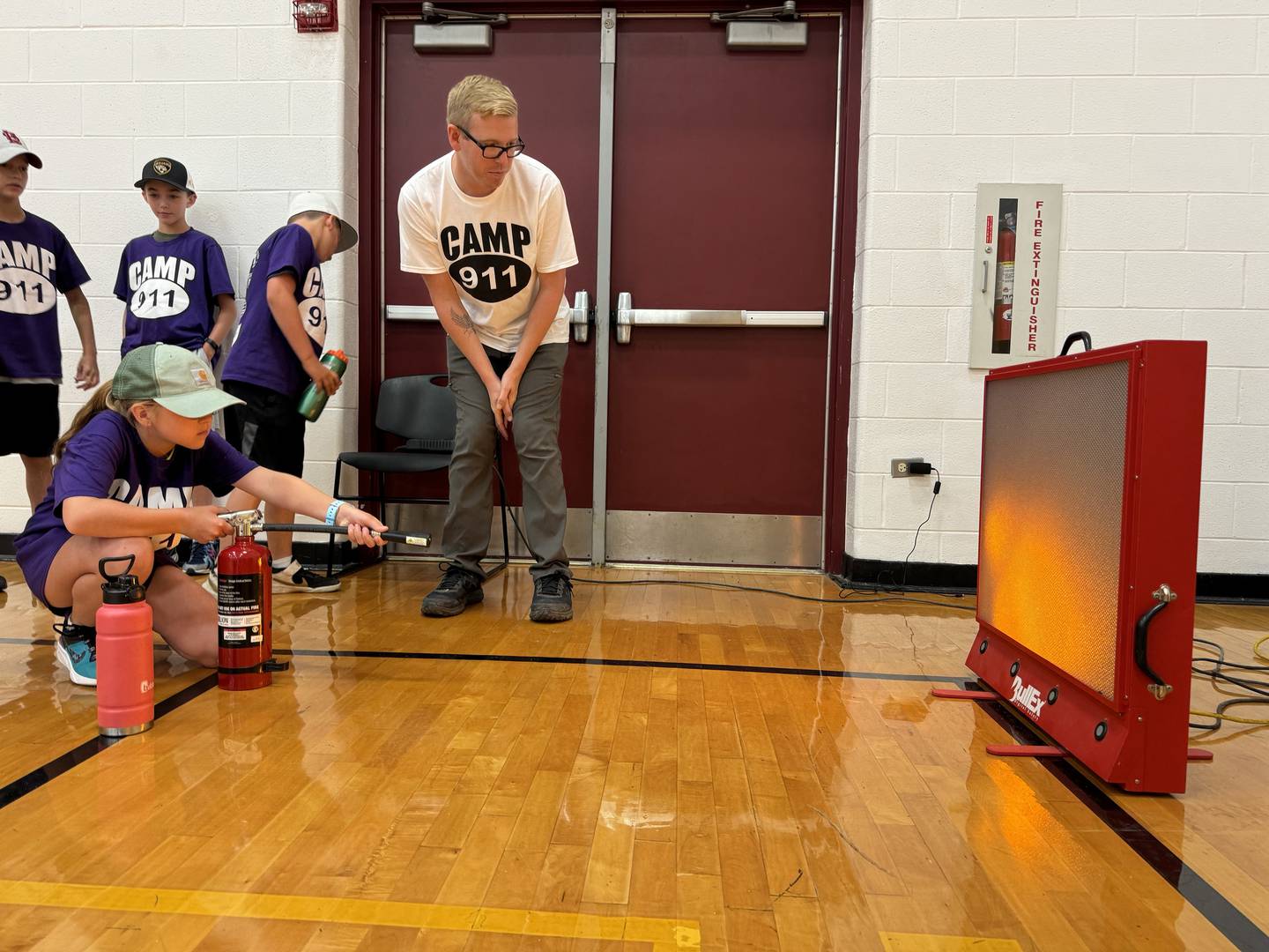 9-year-old Isadora puts out a simulated fire with the help of Jared Darling.