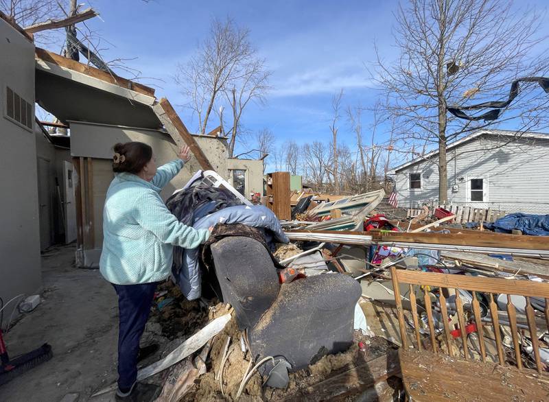 Aroma Park resident Patricia Kime stands in what was her living room at her home on Strasma North Drive recounting the the March 10 EF-3 tornado that destroyed many homes in the area.