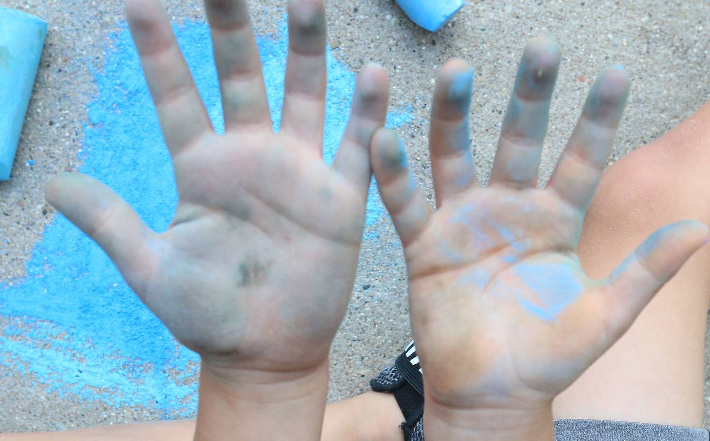 Collin Caputo of Oglesby, shows off his blue covered hands in between coloring the sidewalk in front of the Peru Public Library during their "Chalk the Walk" event on Tuesday, Aug. 13, 2024.