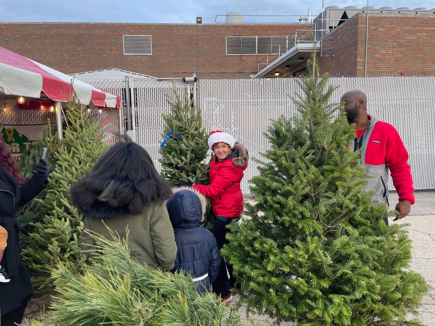 Wendy Richardson of Richardson Christmas Tree Farm, Spring Grove, assists military families in picking out the perfect tree after a Trees for Troops program drop-off at Naval Station Great Lakes.