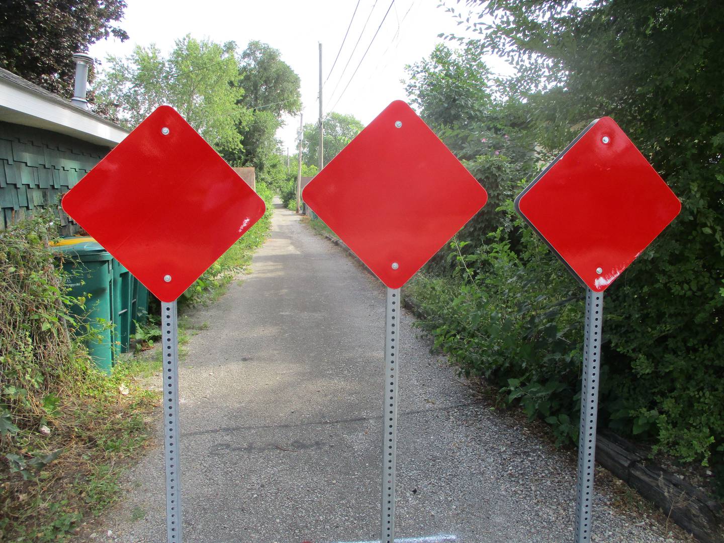 Three posts topped with bright red signs now block access again at the Ingalls Avenue side of the alley that runs behind the 1100 block of Center Street in Joliet. The posts and signs were installed Thursday. Aug. 25, 2023.
