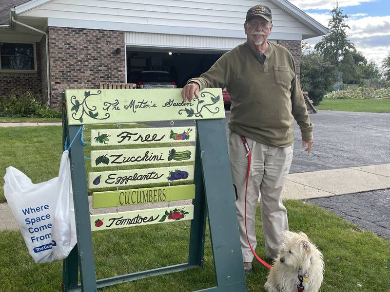 DeKalb resident Ron Marten is seen Sept. 26, 2022 standing outside of his house next to a sign and his dog, Winnie.