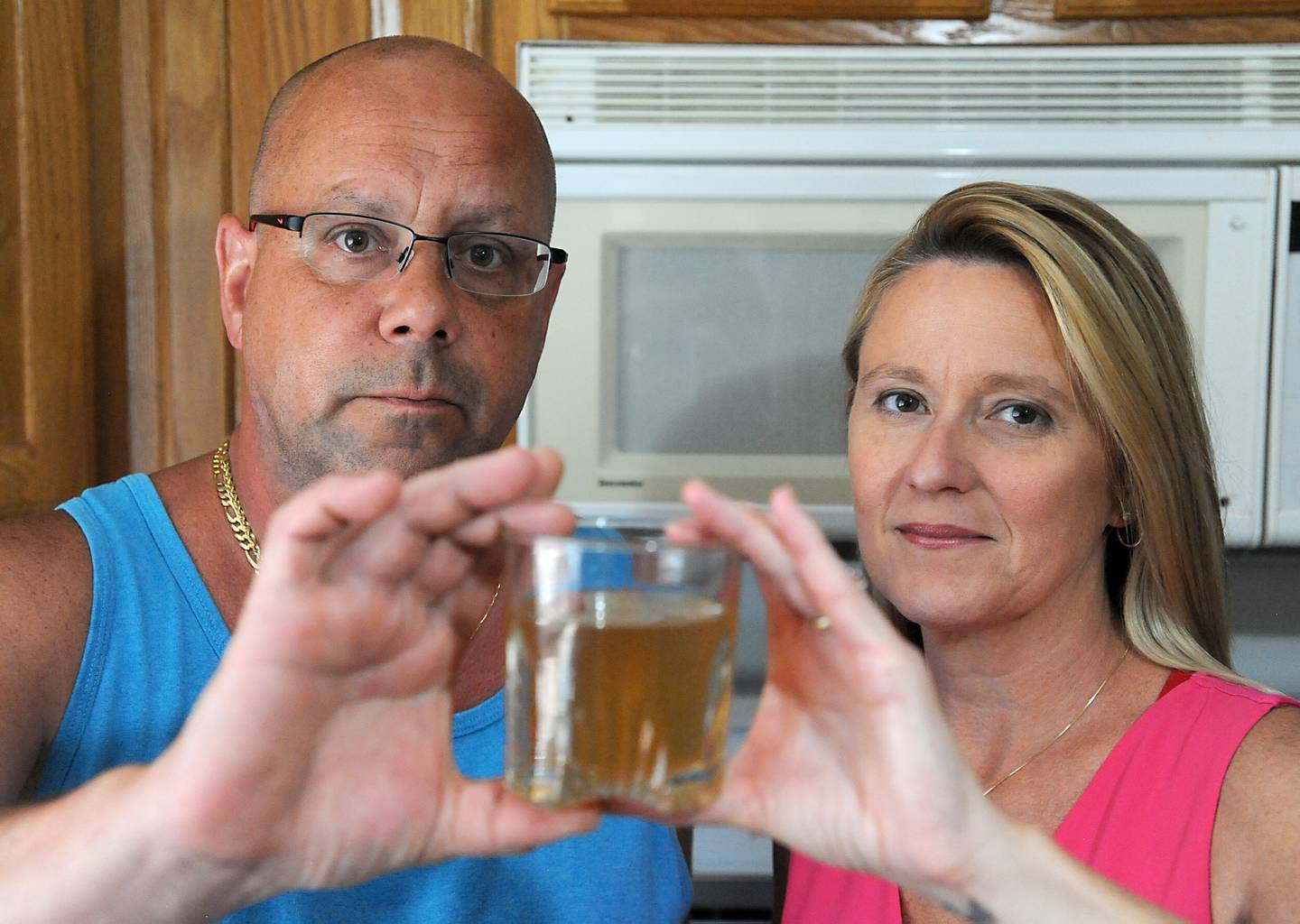 Scott Martens and Sandra Murphy hold a glass of water that comes out of the water utility that serves Johnsburg on Wednesday, June 29, 2022. Residents in Johnsburg are on a private water system and say the clarity and smell of the water can be awful at times.