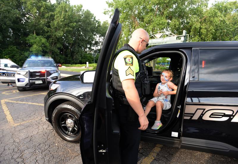 Westmont Police officer Anthony Rainaldi allows children including Addison Britt of Westmont to take a look inside a  police car during Westmont's celebration of National Night Out on Tuesday, Aug 1, 2023.