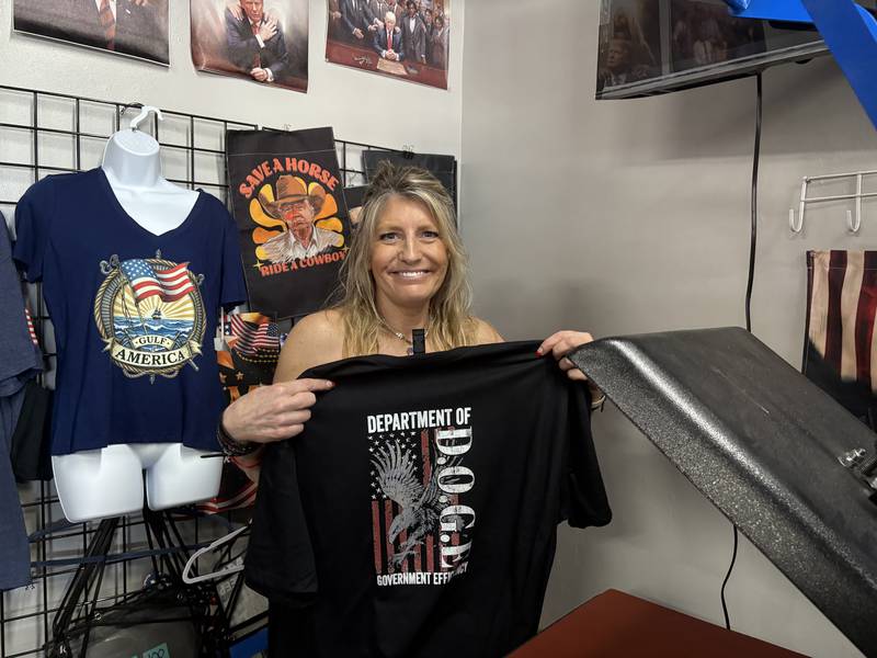 Trump and Truth store owner Lisa Fleischmann holds up a shirt in Huntley May 31, 2025.