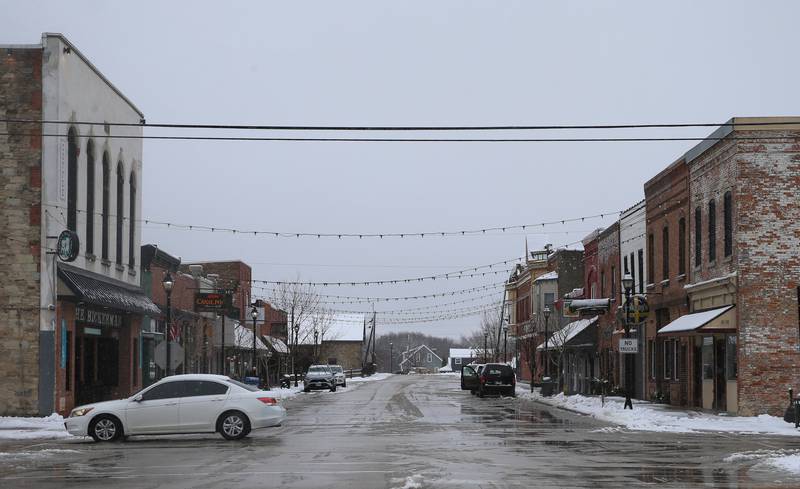 A motorist crosses through the intersection of Mill and Church Streets as light snow falls in the Village of Utica on Tuesday, Jan. 9, 2024.