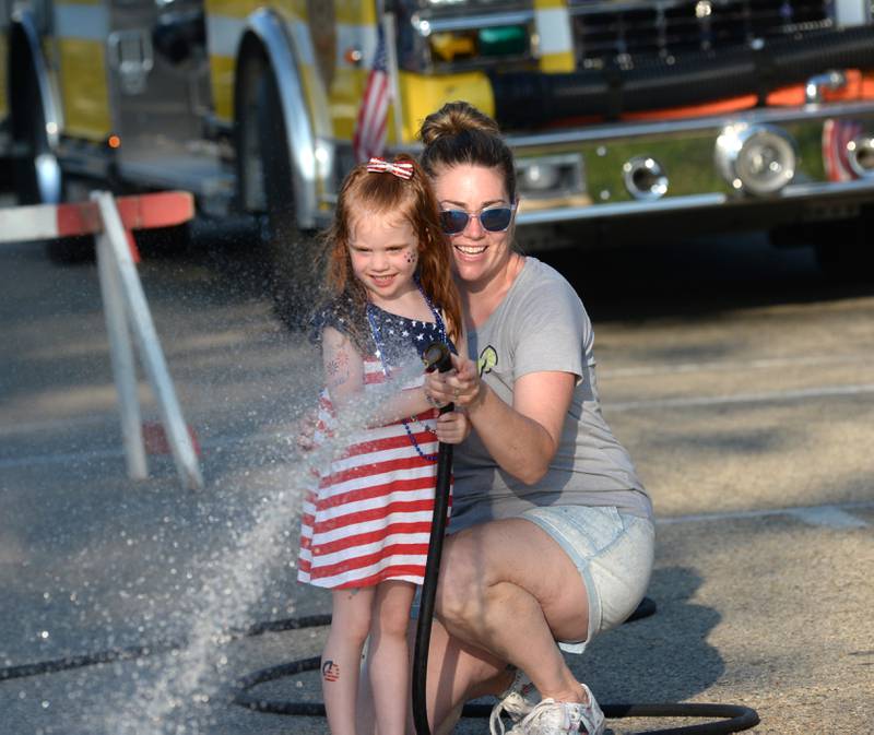 Maeve Hassett, 4, of Centennial, Colorado, gets some help from her mom, Katie, a Mt. Morris native, during the kids' water fight at Let Freedom Ring on Monday. The event was organized by the Mt. Morris Fire Department.