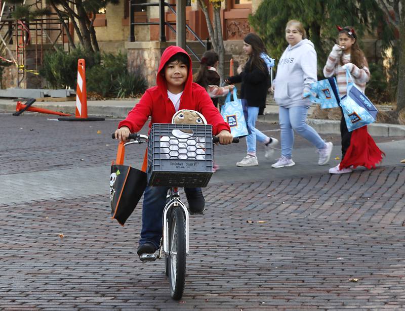 Randy Arias rides his bike with E.T. as he trick or treats during Halloween on the Square on Thursday, Oct. 31, 2024, in Woodstock. The event featured trick and treating and a costume contest.