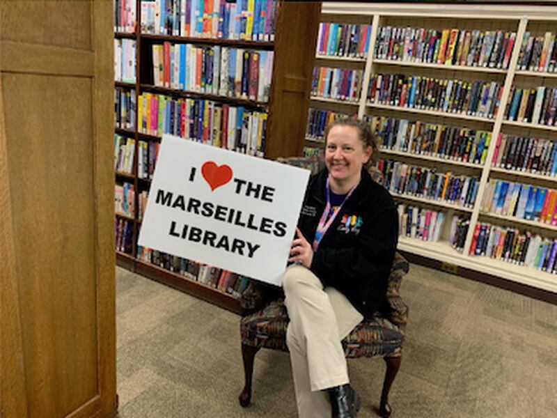 Library Director Heide Trettenero showcases the "I love the Marseilles Public Library" sign available for purchase from the Marseilles Friends of the Library.