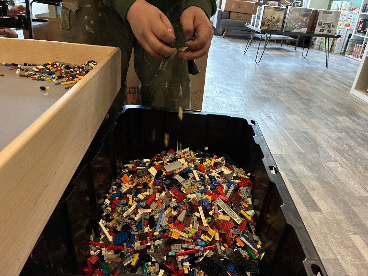 A mover transferred the table of loose Legos into a bin on Tuesday, Feb. 24, 2026, at The Pieceful Project in McHenry. The Lego, puzzle and game store will close this week as owner Jessica Stetson focuses on her Cary location.