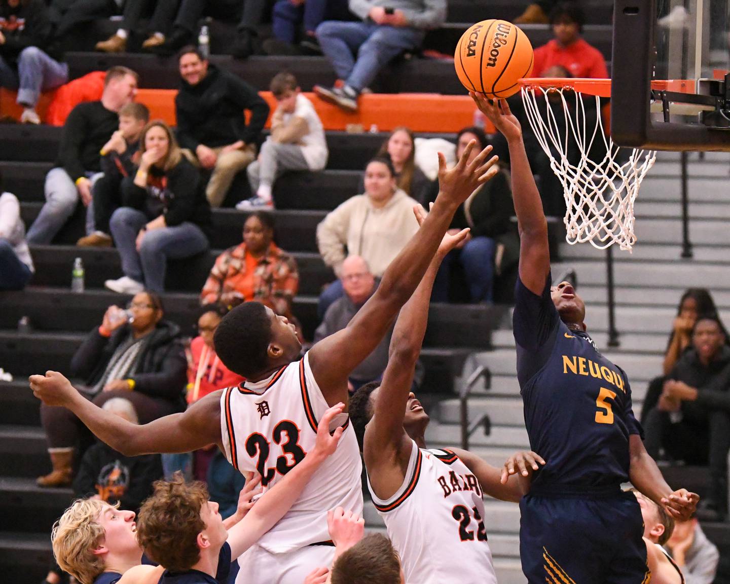 Neuqua Valley's David Taiwo (5) tries to tip in a rebound shot on Saturday Dec. 28, 2024, during the 97th Chuck Dayton Classic championship game held at DeKalb High School while being defended by DeKalb's Davon Grant (23) and teammate Justin O'Neal (22).