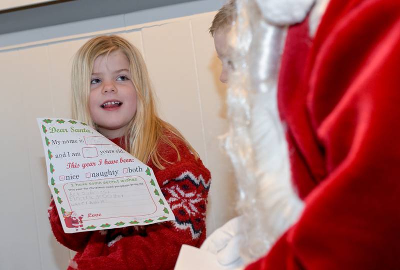 Avery Whitson, 5 presents Santa with her wish list during a visit to SantaÕs Workshop in Geneva of on Saturday, Dec 20, 2025 in Geneva.