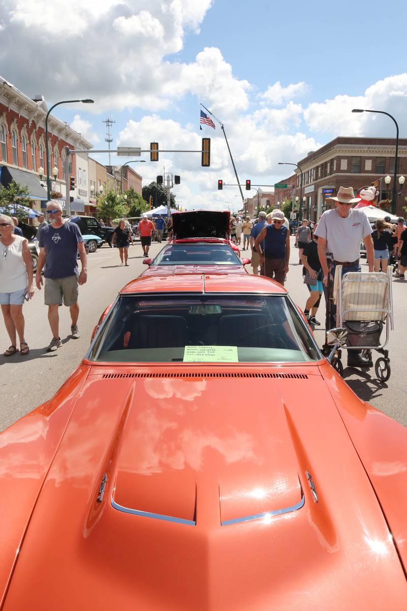 People pass by the line of vehicles on State Street during the Fizz Ehrler Memorial Turning Back Time Car Show Sunday, July 30, 2023, in downtown Sycamore.