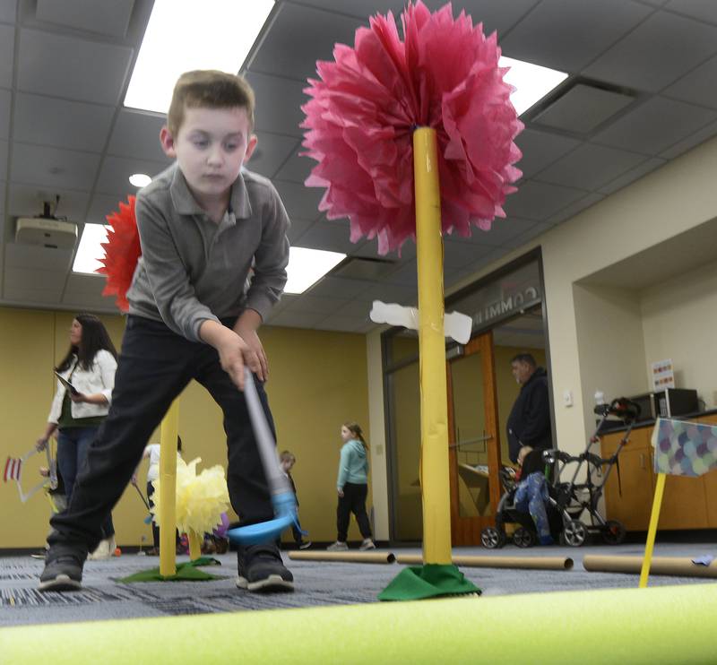 Preston Slonek works to sink a putt Thursday, March 7, 2024, at the Reddick Library in Ottawa during a special Dr. Seuss miniature golf outing to celebrate the author’s March 2 birthday.