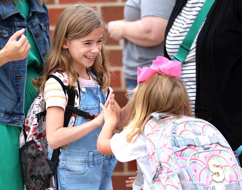 Third grader Rowan Oncken (left) is excited to see her friend, kindergartener Sterling Smith, when she arrives Thursday, Aug. 21, 2025, for the first day of school at North Grove Elementary School in Sycamore.