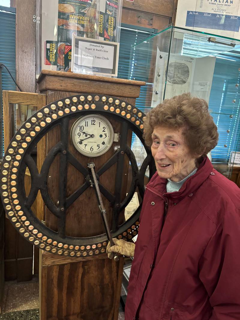 Showing the display and explaining how Nabisco employees moved the time clock wheel to punch their unique number, is Doris Sobinsky, a museum volunteer.  Sobrinsky, who is 98 years old, was employed as a clerk at Nabisco and still knows how to use the time-clock.