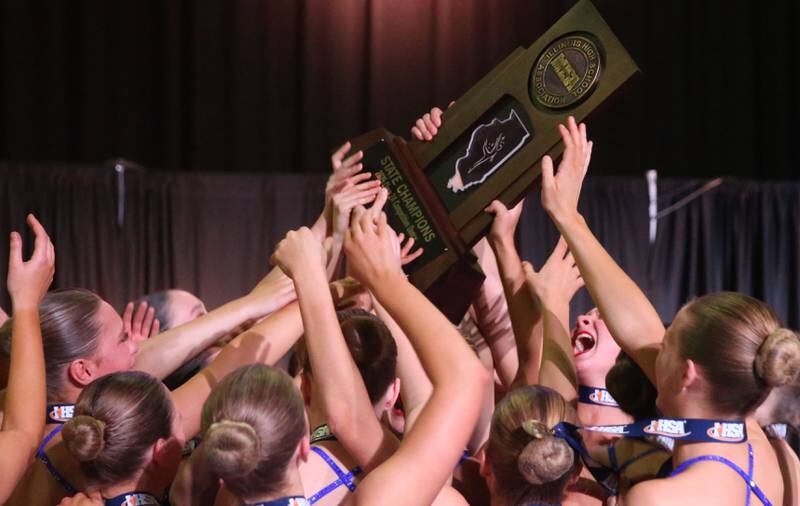 Members of the Geneva High School dance team hoist the Class 2A championshiip trophy during the  IHSA State Dance finals on Saturday, Feb. 1, 2025 at Grossingers Motor Arena in Bloomington.
