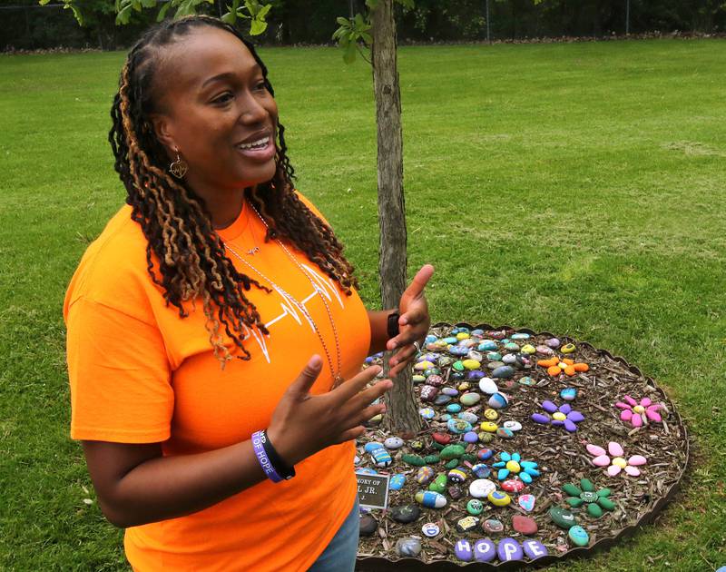 Andrea Elion, mother of Ezra Hill Jr. smiles as she talks Monday, May 12, 2025, about him next to a tree and rock garden at Tyler Elementary School, where he attended, that is dedicated to his memory. Hill was murdered in 2019 in Harvey, and the Fifth Annual Ezra Hill Jr. Memorial Rock Painting event will be held on June 7 at the school in DeKalb.