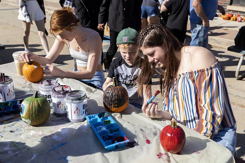 Family members Peyton Book (left), Jayce Hofmaster and Cadence Williamson decorate pumpkins Saturday, Oct. 22, 2022 during Dixon’s Scarecrow Fest. The craft was sponsored by Dixon Paint Company.