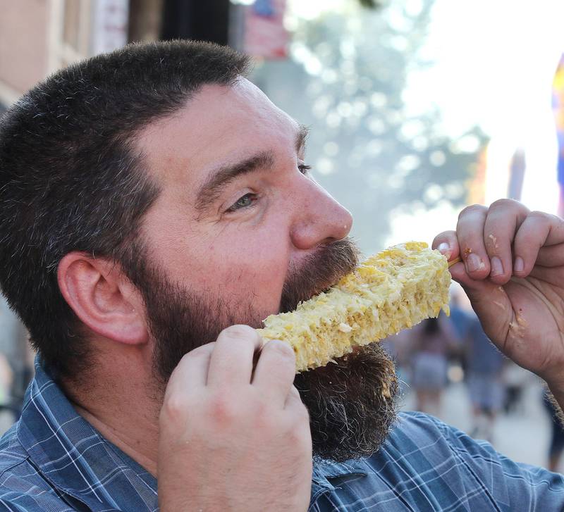 Nate Walters, from DeKalb, enjoys some corn-on-the-cob on Lincoln Highway Aug. 27, 2021, at Corn Fest in downtown DeKalb. The festival runs through Sunday and features rides, food, crafts and entertainment.