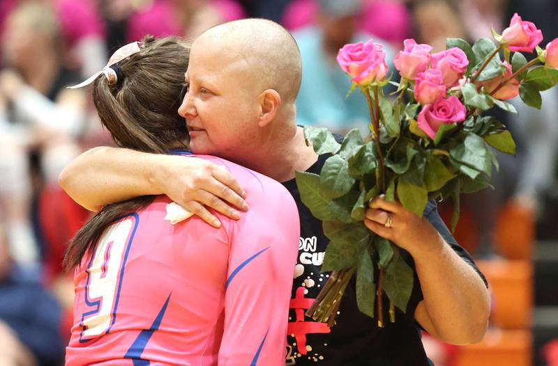 Becky Cleveland receives pink roses from volleyball players as she is recognized as the guest of honor before the Genoa- Kingston volleyball team's Volley for the Cure breast cancer fundraiser match against Oregon Wednesday, Sept. 21, 2022, at Genoa-Kingston High School. Cleveland, a former student and teacher at Genoa-Kingston High School is currently battling cancer.