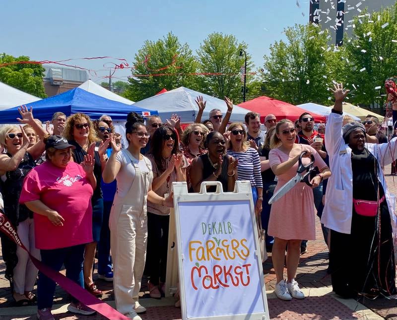 Business owners and members of the DeKalb Chamber of Commerce cheer as a ribbon is cut by the chamber's marketing and events manager Virginia Filicetti to celebrate the 30th year of the DeKalb farmers market on Thursday, June 5, 2025.