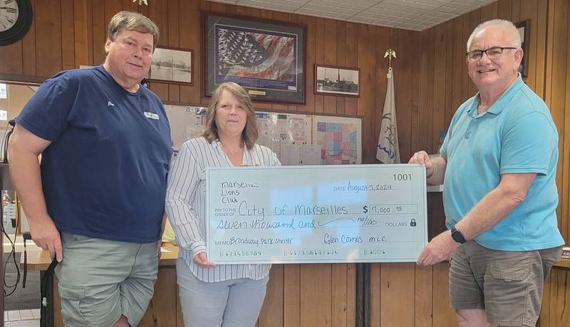 Jim Hanlon and Jodean Peek (from left) present Marseilles Mayor Jim Hollenbeck Wednesday night with a check for $7,000 to be put toward a shelter in the Broadway Park improvement project.