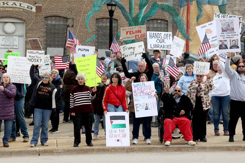 Protesters cheer as passing vehicles honk their horns Saturday, April 5, 2025, as hundreds of people assembled for a Hands Off! rally at Memorial Park on the corner of First Street and Lincoln Highway in DeKalb. The group gathered to protest against various policies of President Donald Trump and his administration.
