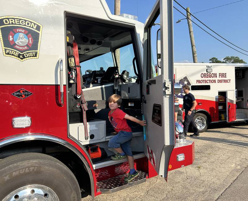 Tayden Quintero, 4, of Oregon, climbs into a cab of an Oregon fire truck during the National Night Out event in Oregon on Tuesday, Aug. 5, 2025 in Oregon. The event was organized by the Oregon Police Department and included displays and trucks provided by the police and public works departments.